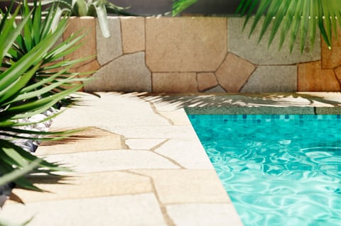 Luxury swimming pool with tropical plants and stone path. Poolside patio in mediterranean holiday villa.