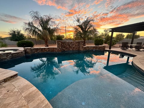 Beautiful desert sunset in an Arizona backyard with a palm tree, pergola / ramada and swimming pool