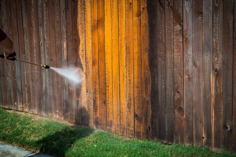 Professional power washing a wooden fence