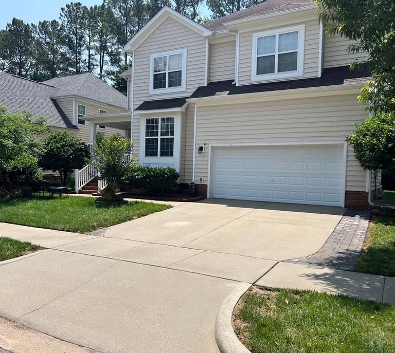 Freshly cleaned concrete driveway with paver border at a two-story home in Wake Forest NC