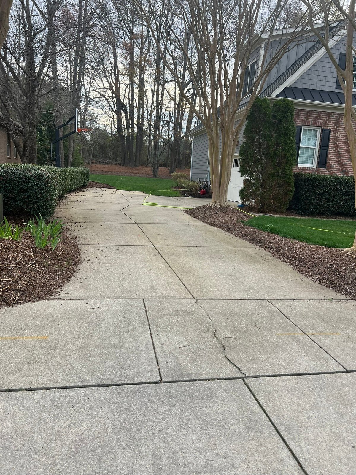 Grey stained concrete driveway with leaf debris in Wake Forest NC before pressure washing