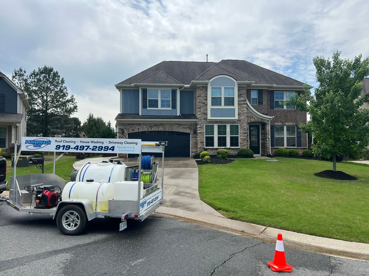 Powerwash Guy branded trailer rig with tank and hose reels at a house washing job in Wake Forest NC