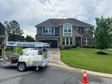 Powerwash Guy branded trailer rig with tank and hose reels at a house washing job in Wake Forest NC